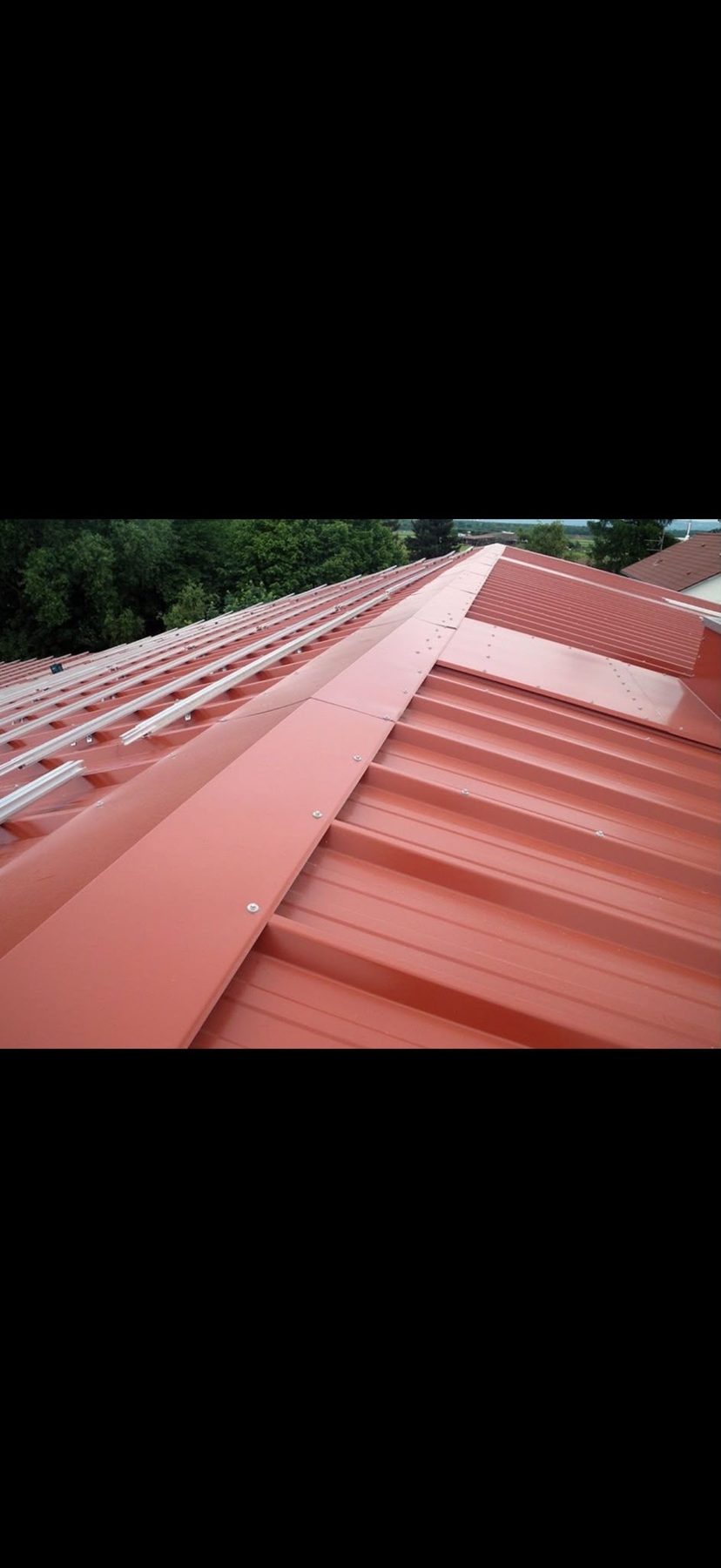 Neue rote Trapezblecheindeckung mit First und Solarschienen