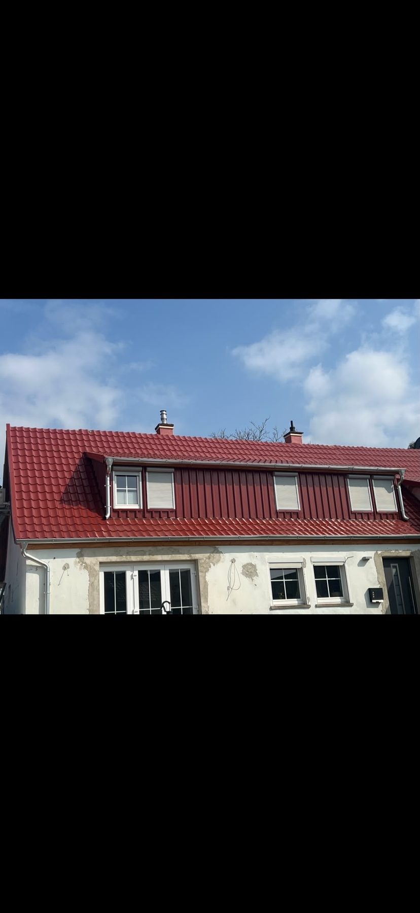 Neue rote Ziegel und rot verblechte Schleppgaube am Wohnhaus